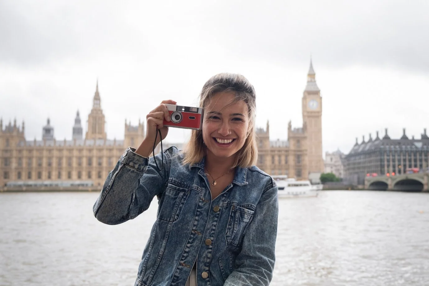 Family laughing together during a professional photoshoot on the South Bank with the London Eye behind.