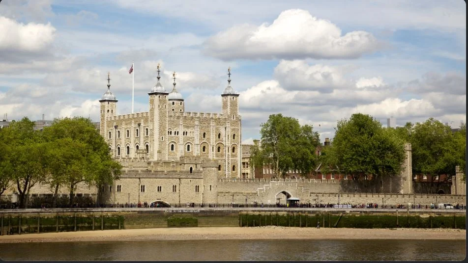 The White Tower and the medieval walls of the Tower of London beside the Thames, with Tower Bridge behind