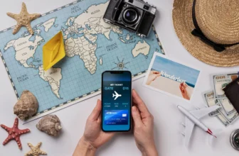 Hands holding a smartphone displaying an airline boarding pass on a travel-themed desk with a world map, passport, camera, and hat