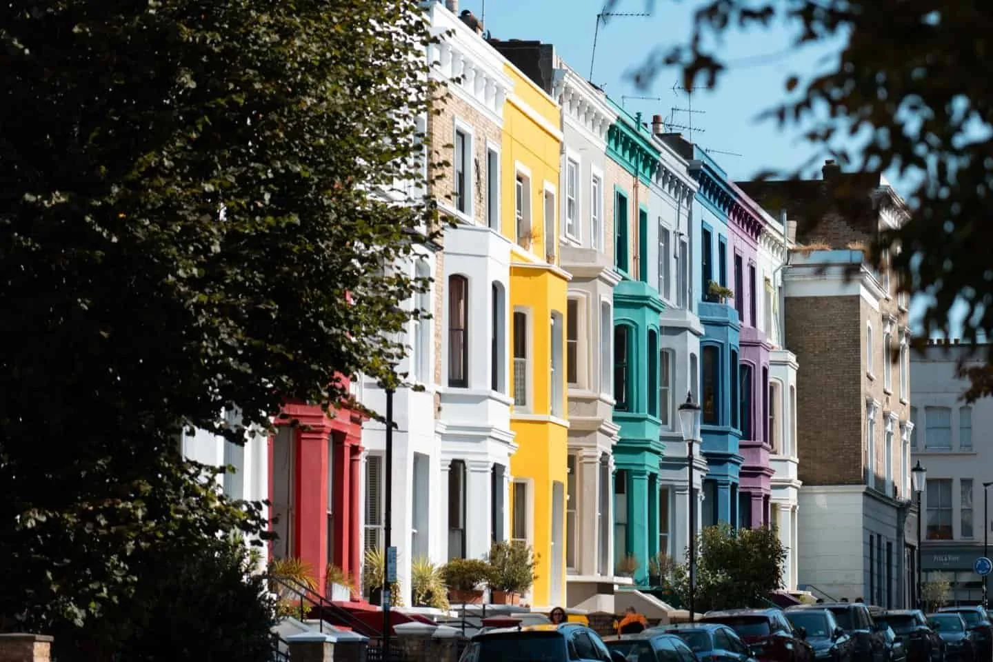 Row of pastel-coloured Victorian houses on a Notting Hill street in London.