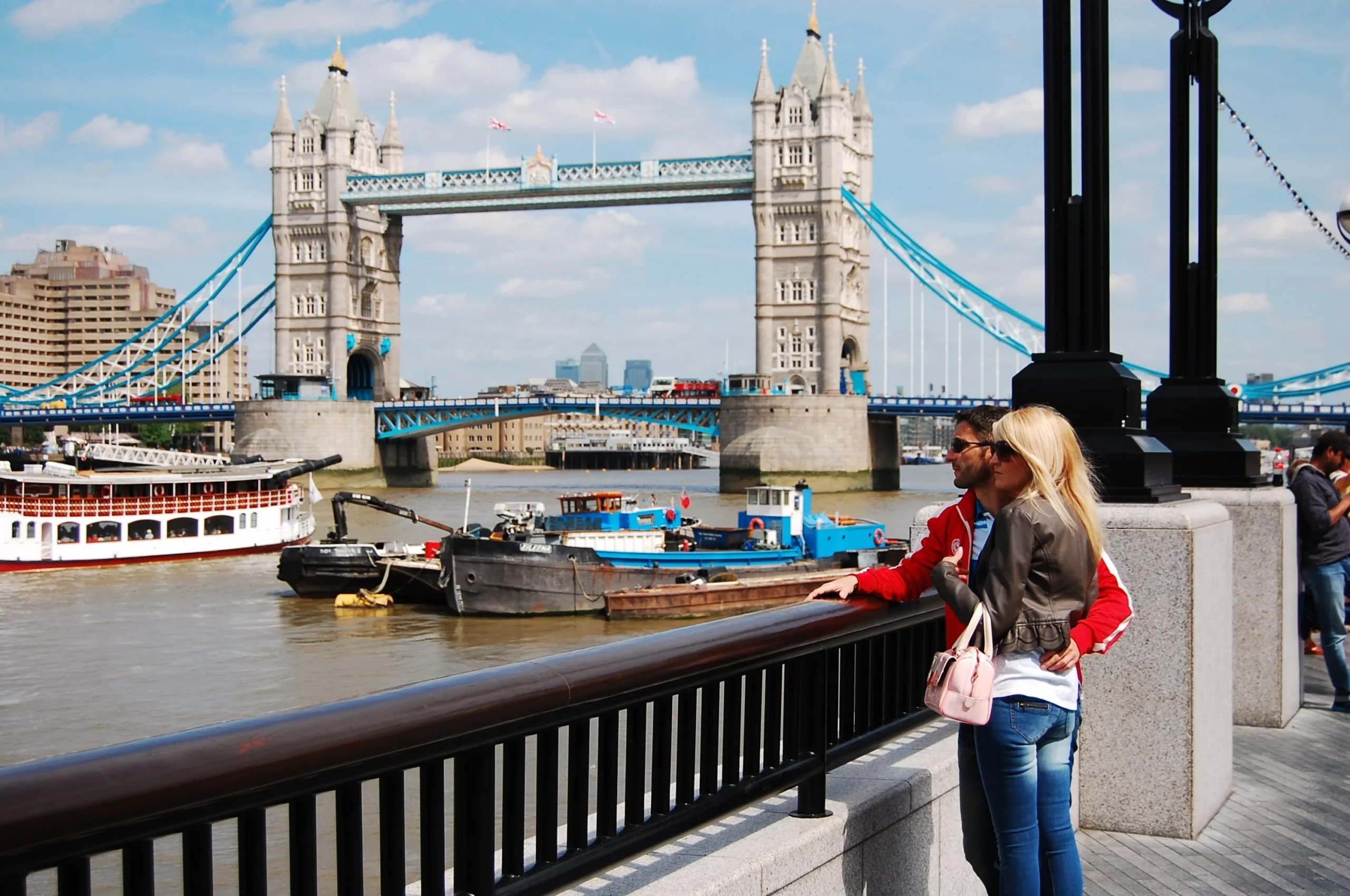 Thames Clipper river boat passing under Tower Bridge with families visible on the top deck.