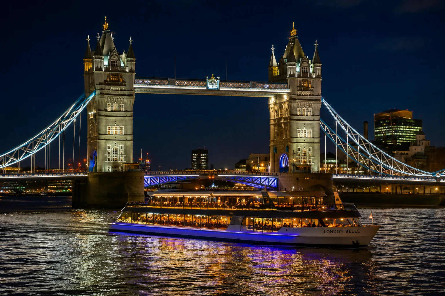 Birthday dinner cruise boat lit up on the River Thames passing Tower Bridge at night.