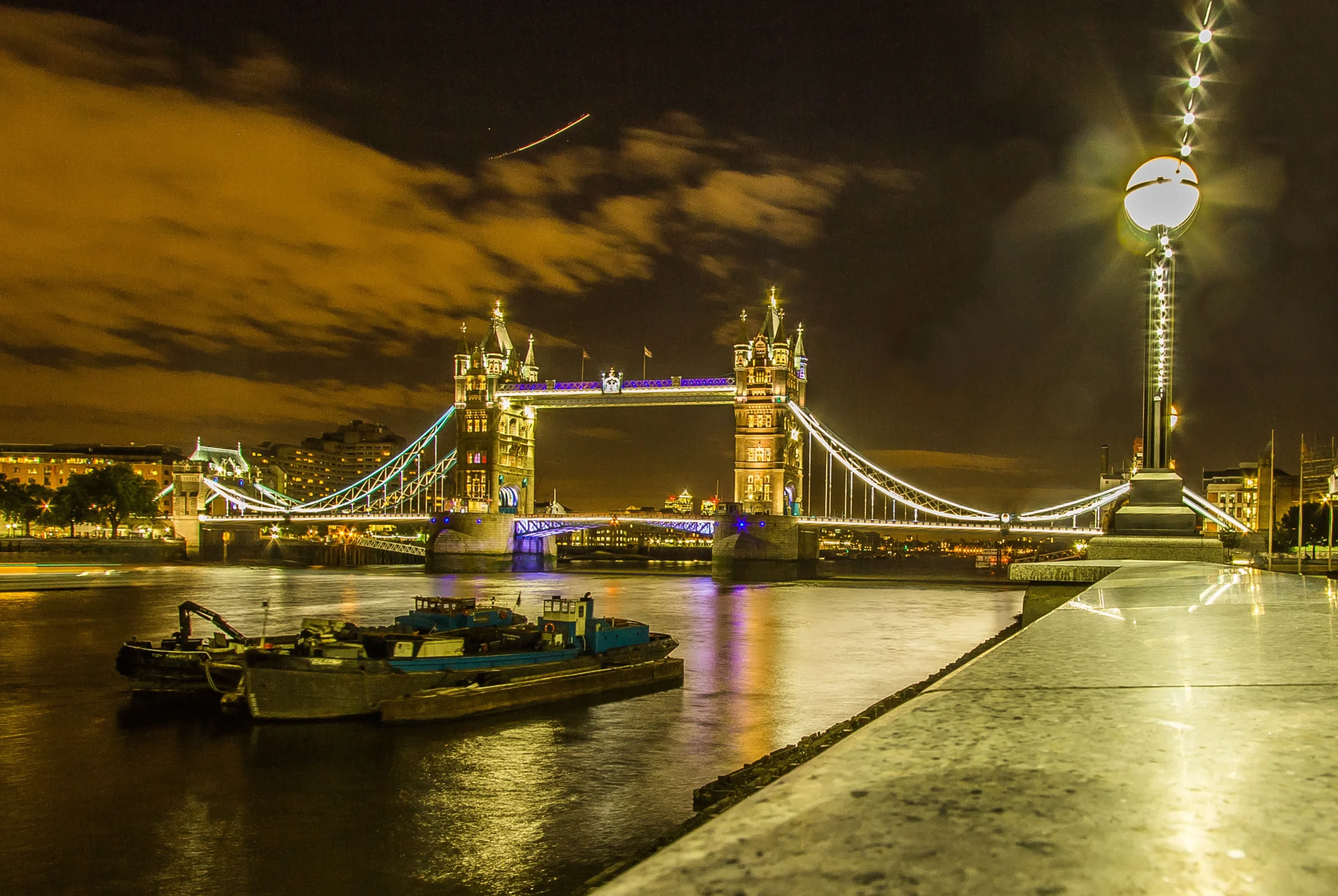 Tower Bridge illuminated at night over the River Thames.
