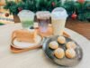 A table of small festive desserts and hot drinks set out beside Christmas decorations