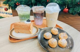 A table of small festive desserts and hot drinks set out beside Christmas decorations